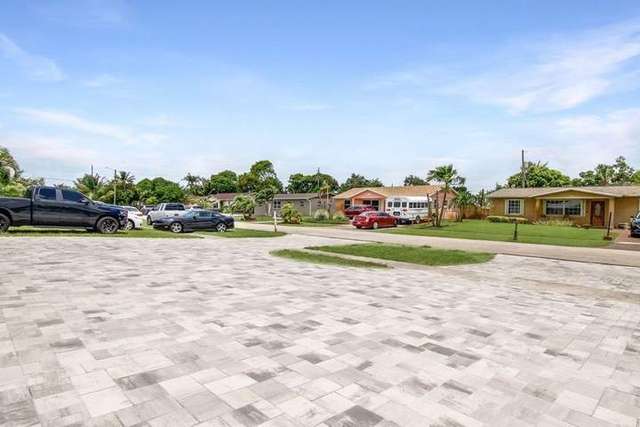 Suburban neighborhood street with single-family homes, parked vehicles, palm trees, and clear sky – Deck & Drive