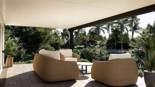 Covered patio with tan woven armchairs, small table, and cream cushioned seating, overlooking lush tropical landscape wi – Deck & Drive